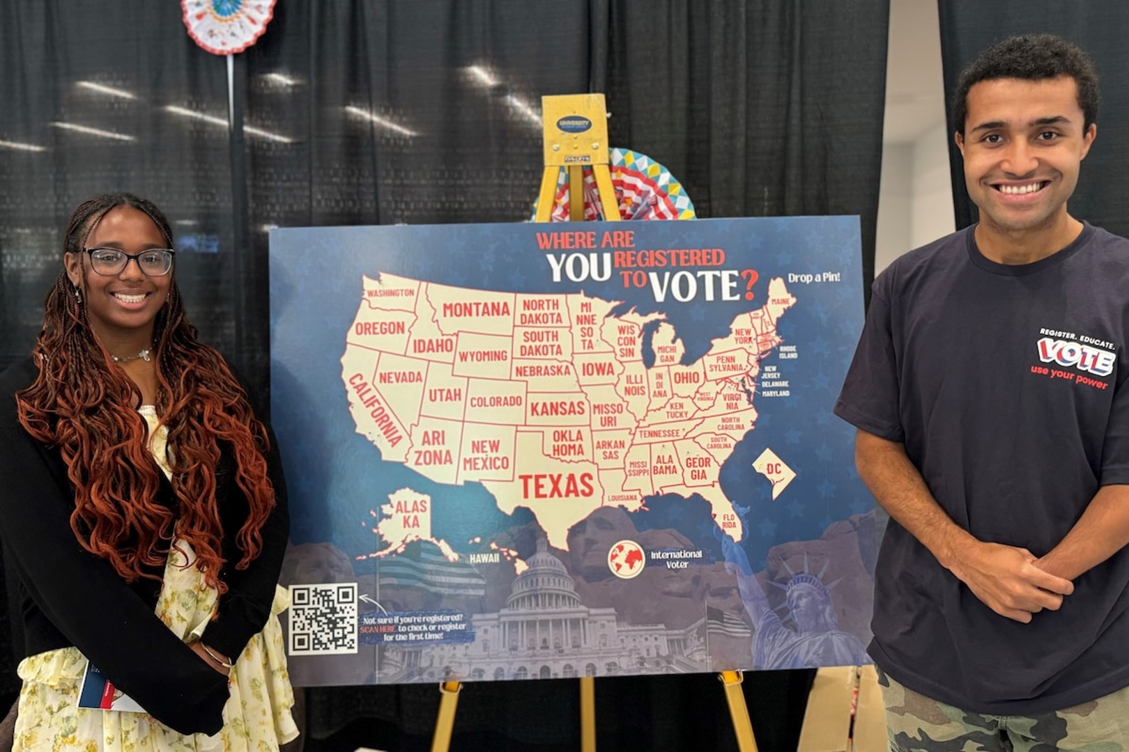 George Washington University students Ariel Pennington-Reyes and Christian Williams flank a board with pins marking where students have registered to vote. (Tamilore Oshikanlu/The Washington Post)
