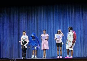DCPS students on a stage presenting about an anti cyberbullying campaign 