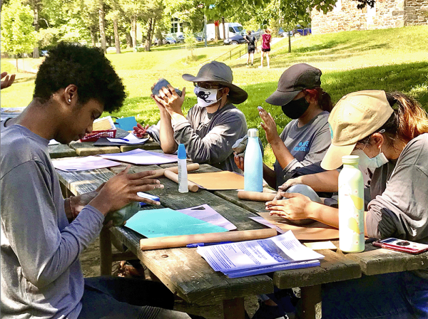 Students working on a project at a picnic table in a park